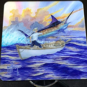 Puede incluir: Una pintura de acuarela de un hombre en un bote que está pescando un gran marlin azul. La escena se desarrolla en un cielo de puesta de sol colorido con nubes. La pintura está firmada "Guy Harvey" en la esquina inferior izquierda.