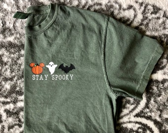 May include: A green t-shirt with a pumpkin, ghost, and bat graphic. The text "STAY SPOOKY" is printed below the graphic.