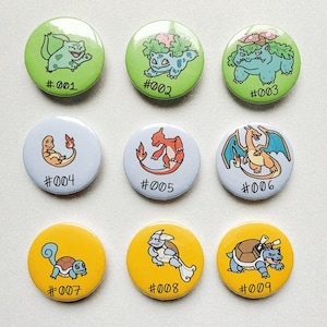 Peut inclure: Neuf boutons ronds avec différents personnages Pokémon. Les boutons sont numérotés de #001 à #009.