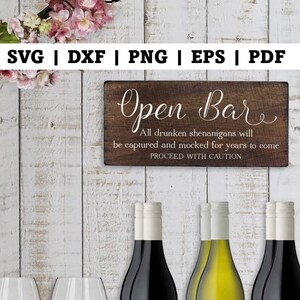 May include: A wooden sign with the text "Open Bar" in a cursive font. The sign also includes the text "All drunken shenanigans will be captured and mocked for years to come. Proceed with caution."