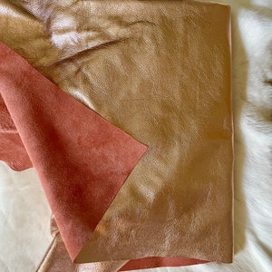 May include: A piece of rose gold leather with a pink suede backing. The leather is folded in half and the suede is visible on the outside.