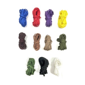 Puede incluir: Surtido de 10 carretes de cordón de colores, incluyendo rojo, azul, amarillo, verde, marrón, negro y blanco. Los cordones son todos del mismo tamaño y están dispuestos en una fila.
