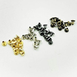 May include: Assortment of metal eyelets in gold, silver, and black. The eyelets are small and have a round shape with a raised lip. They are commonly used for crafts and leatherwork.