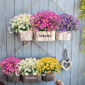 Pode incluir: Seis arranjos de flores artificiais em vasos de madeira pendurados em uma parede de madeira cinza. As flores s&atilde;o brancas, amarelas, rosas e roxas. Os vasos t&ecirc;m a palavra "SPRING" escrita neles.