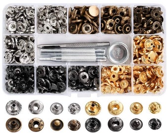 Può includere: Una scatola di plastica trasparente piena di bottoni a pressione in metallo di diverse dimensioni e colori. La scatola include due strumenti in metallo per fissare i bottoni a pressione.