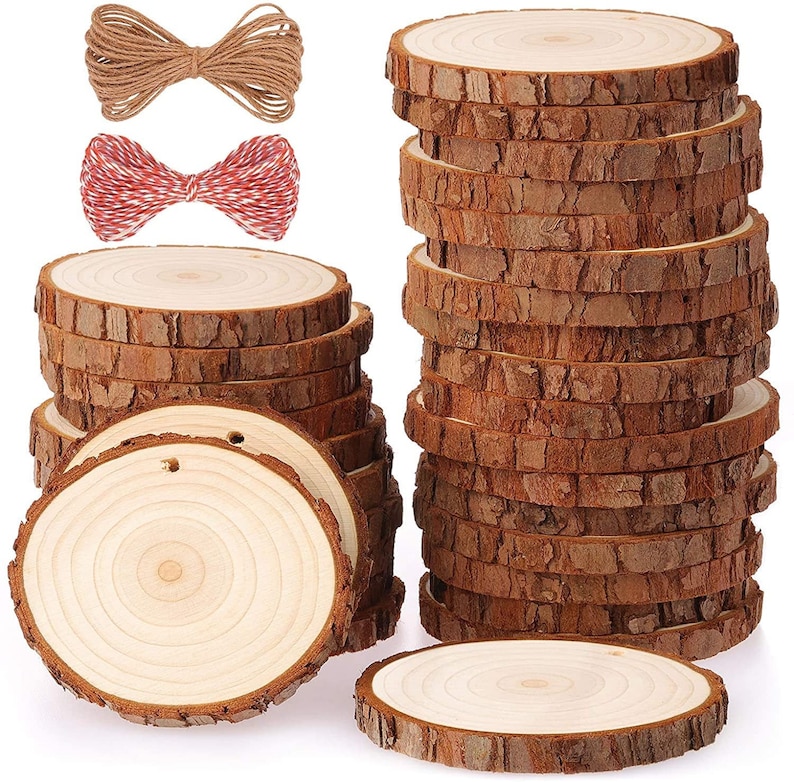 May include: A collection of unfinished wooden slices with natural bark edges, ideal for crafts. Two bundles of twine, one brown and one red and white, are also included. The wood rounds vary in size and have a light wood grain.