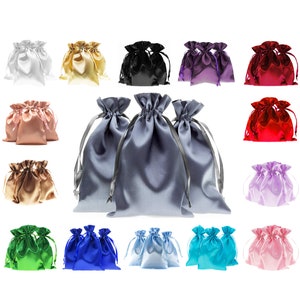 Puede incluir: Surtido de 15 bolsas de cordón de satén en varios colores, incluyendo blanco, dorado, negro, morado, rojo, rosa, azul claro, turquesa, verde y azul. Las bolsas están dispuestas en tres filas de cinco.