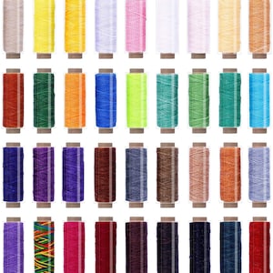 Peut inclure: Un ensemble de 40 bobines de fil ciré de différentes couleurs, notamment beige, jaune, blanc, rose, vert, orange, bleu, rouge, violet, marron et noir. Les bobines sont disposées en quatre rangées de dix, et chaque bobine est dans un récipient en plastique transparent.