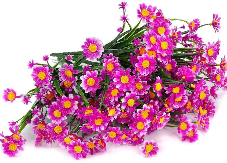 Pode incluir: Um ramo de flores de margarida artificiais cor-de-rosa com centros brancos. As flores est&atilde;o dispostas em um ramo e t&ecirc;m caules verdes.