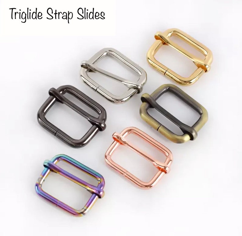 May include: Six different colored metal triglide strap slides. The slides are rectangular with a metal loop on each side. The colors are gold, silver, black, bronze, rose gold, and rainbow.