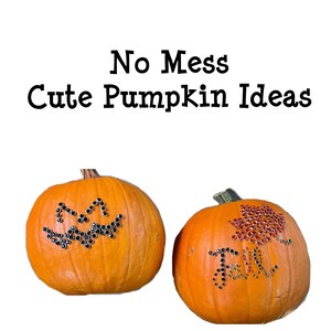 Op de afbeelding: Twee oranje pompoenen versierd met strass. Eén pompoen heeft een zwart strass gezicht en de andere heeft een rood en gouden strass "Herfst" ontwerp.