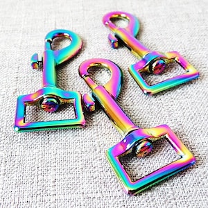 May include: Three iridescent rainbow-colored metal clasps with a rectangular loop and a spring-loaded gate.