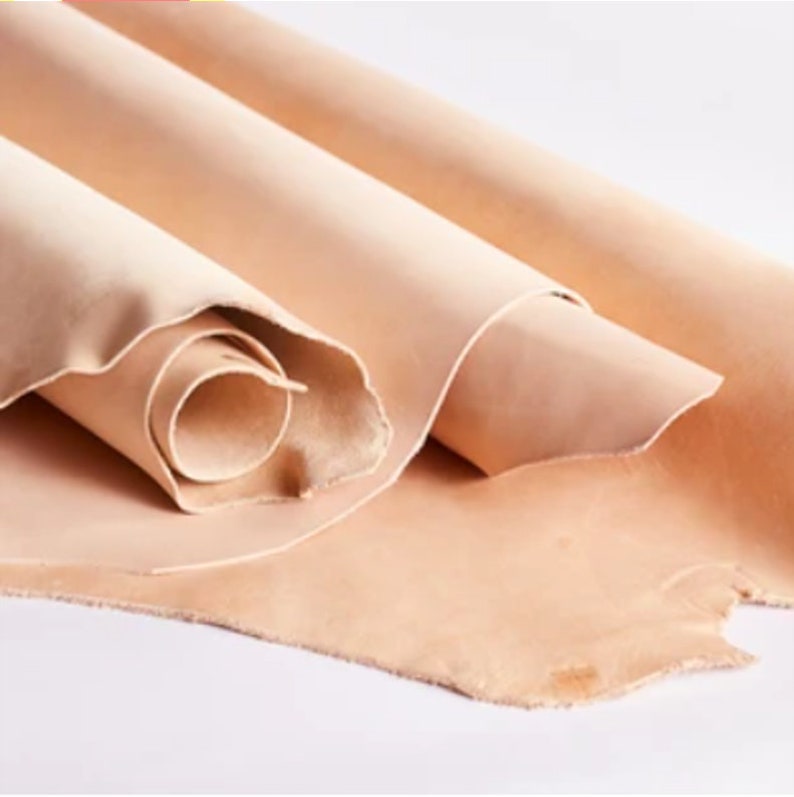 May include: Close-up of a stack of light brown leather hides. The leather is soft and supple, with a natural grain.