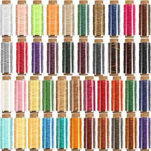 Puede incluir: Un conjunto de 48 carretes de hilo encerado en varios colores, incluyendo blanco, rosa, amarillo, verde, naranja, marr&oacute;n, azul, rojo, morado, negro y gris. Los carretes est&aacute;n dispuestos en filas y todos est&aacute;n en contenedores de pl&aacute;stico transparente con tapas marrones.