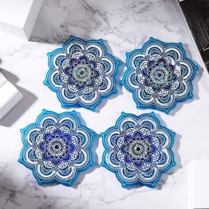 Puede incluir: Cuatro posavasos de mandala azul y blanco con diseños intrincados. Los posavasos están hechos de resina y tienen un acabado brillante.