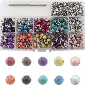 May include: A set of 10 different colored round metal studs with a silver base. The studs are in a clear plastic storage box with a tool for setting the studs. The studs are arranged in rows of 10, with each row containing a different color. The colors are black, turquoise, red, green, white, purple, orange, yellow, brown, and pink.