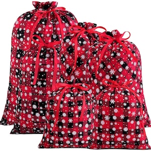Pode incluir: Conjunto de cinco sacos de presente de Natal vermelhos e pretos com padrões de flocos de neve brancos. Os sacos são feitos de tecido e têm cordões com fita vermelha.