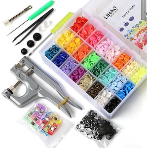 Puede incluir: Un juego de botones a presión de colores en una caja de almacenamiento de plástico transparente con una herramienta para sujetarlos. El juego también incluye un par de pinzas, un pequeño destornillador y una bolsa de botones a presión negros.
