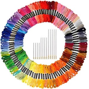 May include: A set of 100 embroidery floss spools in a rainbow of colors, arranged in a circle with the ends of the spools facing outward. The spools are arranged in a gradient from red to purple. In the center of the circle are 18 embroidery needles.