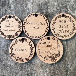 May include: Five round wooden ornaments with a floral design and personalized text. The text includes names, dates, and the phrase "Personalize Me!"