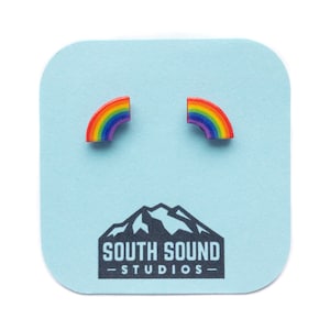 May include: A pair of rainbow-colored stud earrings on a light blue card with the text "South Sound Studios".