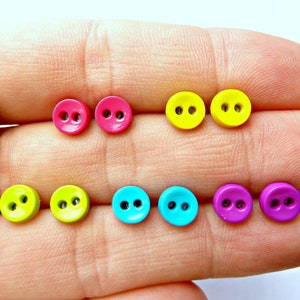 May include: Eight colorful plastic buttons with two holes each. The buttons are arranged in two rows of four. The colors are pink, yellow, green, blue, and purple.