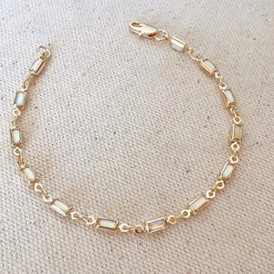 May include: A gold chain bracelet with rectangular white mother-of-pearl stones.