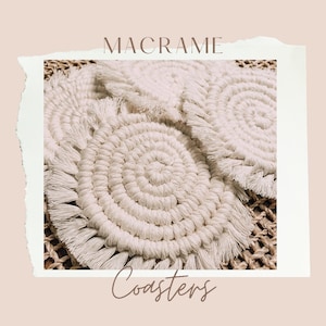 May include: Set of three white macrame coasters with fringe. The coasters are round and have a woven pattern. The coasters are on a woven surface.