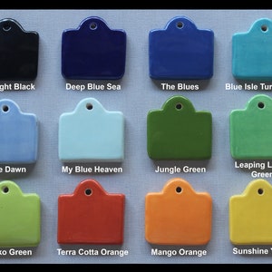 May include: Twelve ceramic tiles with different colors and names. The tiles are arranged in four rows of three tiles each. The colors are midnight black, deep blue sea, the blues, blue isle turquoise, blue dawn, my blue heaven, jungle green, leaping lizard green, gecko green, terra cotta orange, mango orange, and sunshine yellow.