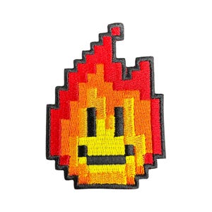 May include: A pixelated flame with a smiling face, embroidered in red, orange, and yellow thread.