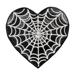 Pode incluir: Patch preto em forma de coração com um design de teia de aranha branca.