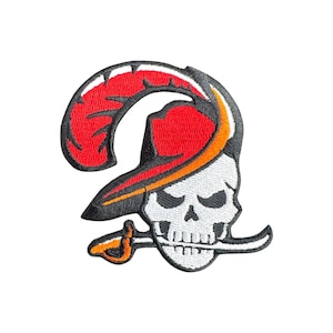 May include: Embroidered patch featuring the Tampa Bay Buccaneers logo. The design includes a white skull wearing a red pirate hat with a black brim and a curved sword in its mouth. The logo is outlined in black.