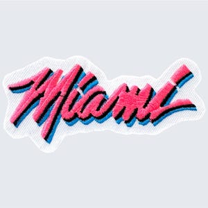 May include: Embroidered patch featuring the word "Miami" in pink, blue and black lettering on a white background.
