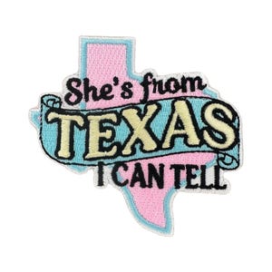 May include: Embroidered patch in the shape of Texas, with a pink outline and a light blue top. The patch reads "She's from TEXAS I CAN TELL" in black and yellow lettering.