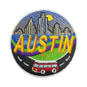 Puede incluir: Parche bordado con la palabra "AUSTIN" en amarillo, sobre un degradado arcoíris, un paisaje urbano y un autobús rojo en una carretera. El parche incluye "TX" y un cielo azul con un sol amarillo.
