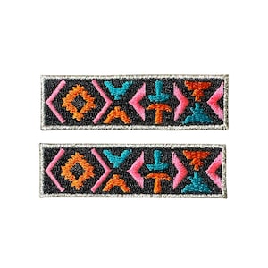 May include: Two rectangular embroidered patches with a black background and a geometric design in orange, pink, and teal. The patches have a silver border and are displayed on a white background.
