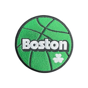 May include: A circular green patch with a basketball design and black lines. The word "Boston" is embroidered in white. A white shamrock is in the lower right corner. The patch has a black border.