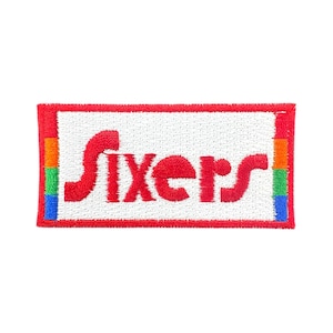 May include: Embroidered patch featuring the word "Sixers" in red, set against a white background. The patch has a red border and rainbow-colored stripes on the left and right edges. The patch is rectangular.