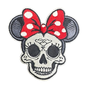 May include: Embroidered iron-on patch featuring a white skull with black eyes and a red bow with white polka dots. The skull has a sugar skull design with black details.