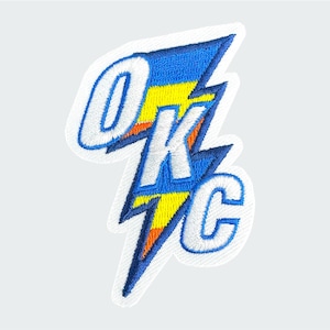 May include: Embroidered patch featuring the letters "OKC" in white, outlined in blue, and set against a blue and yellow lightning bolt design. The patch has a white border and is likely for apparel or accessories.