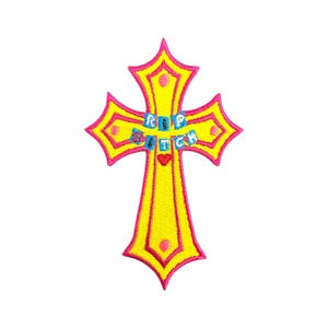 Pode incluir: Uma cruz amarela com contornos rosa e uma inscrição colorida "RIP NITCH". A cruz é um símbolo popular na moda e na cultura.