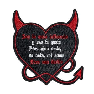Puede incluir: Parche de hierro bordado en negro y rojo en forma de corazón con cuernos de diablo. El texto dice "Son la mala influencia y eso te gusto Lees nina mala, se nofa, mi amor Lees una diobla".