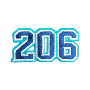 Könnte beinhalten: Gestickter Aufnäher mit der Zahl "206" in einem kräftigen College-Stil. Die Zahlen sind hauptsächlich dunkelblau mit hellblauen Umrissen und weißen Akzenten, vor weißem Hintergrund. Ideal für Jacken, Taschen oder andere Textilien.