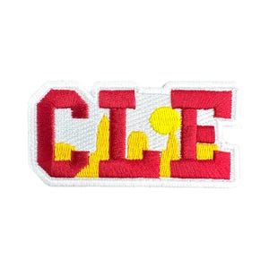 Op de afbeelding: Geborduurde patch met de letters "CLE" in rood en geel, omlijnd met wit. De letters zijn gestileerd in een vetgedrukte, blokkerige lettertype. Geschikt voor kleding of accessoires.