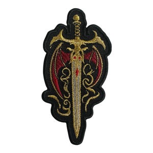May include: A black embroidered patch with a gold sword and red wings. The sword has a silver blade and a gold hilt. The wings are spread out behind the sword.