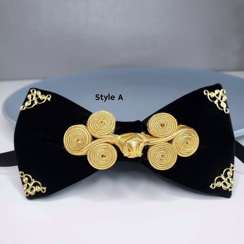 May include: Black velvet bow tie with a gold decorative knot. The knot is made of multiple intertwined loops. The bow tie has a "Style A" label.