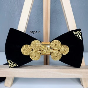 May include: Black velvet bow tie with a gold decorative design. The design features a series of interlocking circles and a gold buckle. The bow tie is labelled "Style B".