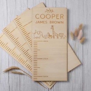 Könnte beinhalten: Ein hölzerner Wachstumsmesser mit einem Giraffen-, Elefanten-, Löwen- und Tigerdesign. Die Karte ist mit dem Namen "COOPER JAMES BROWN" personalisiert und hat Maße in Zentimetern.