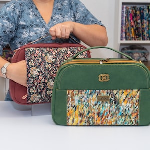 May include: Two rectangular handbags. One is burgundy with a floral pattern, the other is green with a colorful abstract design. Both have top handles, zippers, and decorative hardware.