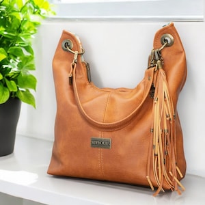 May include: A brown leather tote bag with a fringe detail and a metal tag that says "SEWYOURS".